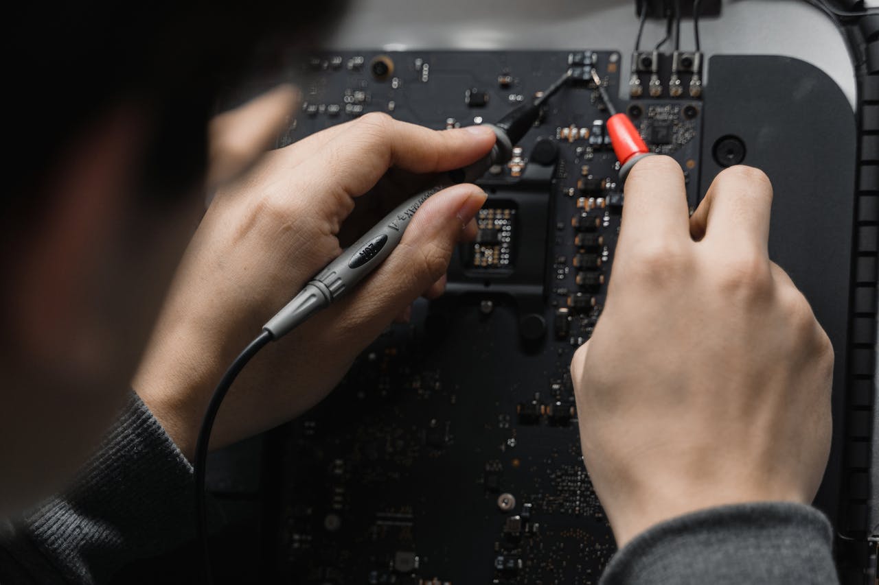 About Close-up of hands repairing a circuit board using a soldering iron, emphasizing technical skill.